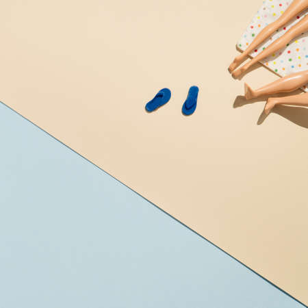Summer scene with sunbathing towel and flip flops. Doll legs creative concept flat lay.の写真素材