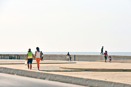 HAVANA, CUBA, MAY 9, 2009  People walking on Malecon beach boulevard and a woman standing on the edge of the boulevard in Havana, Cuba, on May 9th, 2009 のeditorial素材