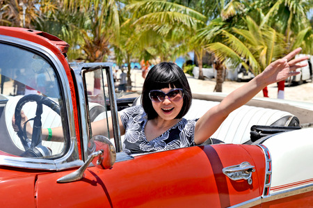 HAVANA, CUBA, MAY 5, 2009  A young Chinese reporter waving out her hand in an old american car, in Havana, Cuba, on May 5th, 2009 のeditorial素材