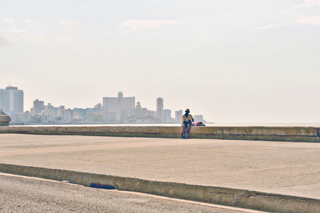 HAVANA, CUBA, MAY 9, 2009  People walking on Malecon beach boulevard and a woman standing on the edge of the boulevard in Havana, Cuba, on May 9th, 2009 のeditorial素材