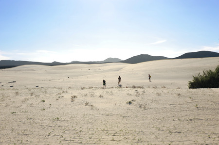 Sand dunes with mountains and blue sky with some thin clouds in the horizon on a sunny day, in Fuerteventura, Canary Islandsの写真素材