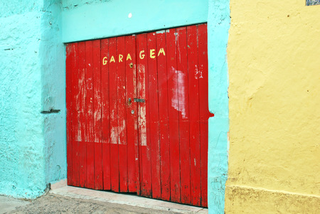 OLINDA, RECIFE, BRAZIL, SEPTEMBER 1, 2009  A colourful red garage door in a truquoise and yellowinsh wall, in Olinda, Recife, Brazil, on September 1st, 2009 のeditorial素材