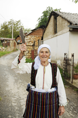 OHRID, MACEDONIA, MAY 17, 2011  An old Macedonian lady posing in a national suit with a butchers knife in her hand, in the countryside of Ohrid, Macedonia, on May 17th, 2011のeditorial素材