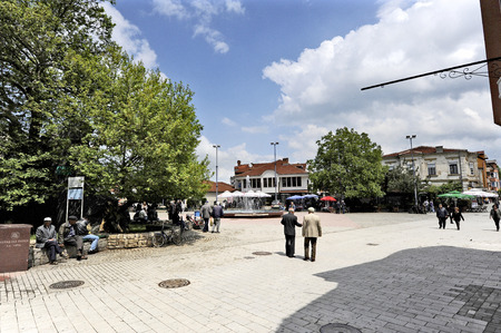 OHRID, MACEDONIA, MAY 17, 2011  People walking on the town square of the town of Ohrid in Ohrid, Macedonia, on May 17th, 2011  Houses, a tree, a fountain and a minaret in the background のeditorial素材