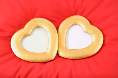two gold hearts are situated on red pillowの写真素材