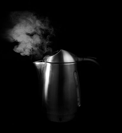 steam against black background and boiling water in a silver tea kettleの写真素材