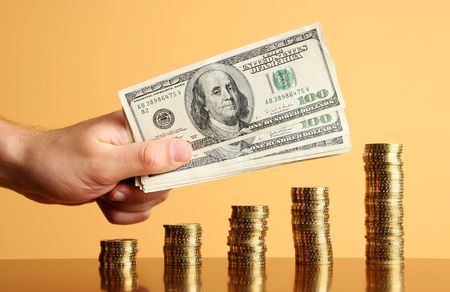 five towers of gold coins and hand with dollars