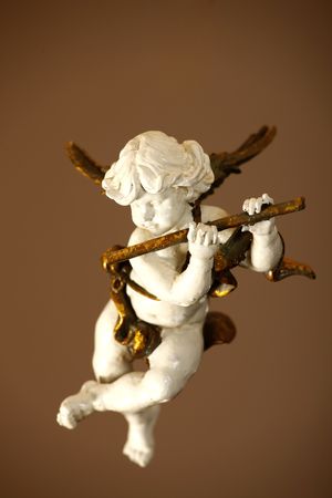 porcelain angel playing the flute over brown background