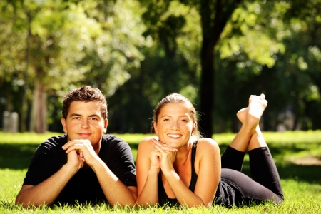 A young nice couple resting in the park and smiling over natural backgroundの写真素材