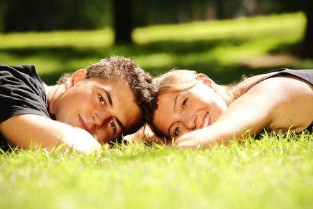 Young couple lying in the park and smilingの写真素材