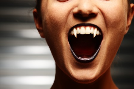 Close up of a vampire woman's mouth over dark backgroundの写真素材