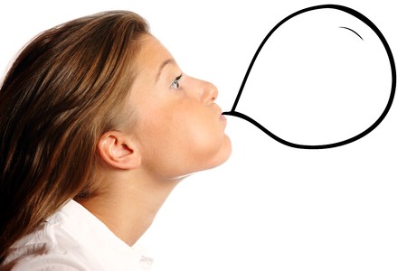 Young nice woman blowing a baloon over white background, a lot of space for textの写真素材