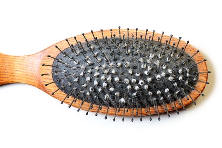 A close-up of a dirty hairbrush over white background