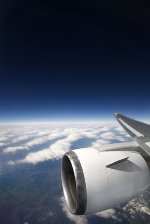 A picture of a plane engine up in the sky with the Earth and blue sky in the background