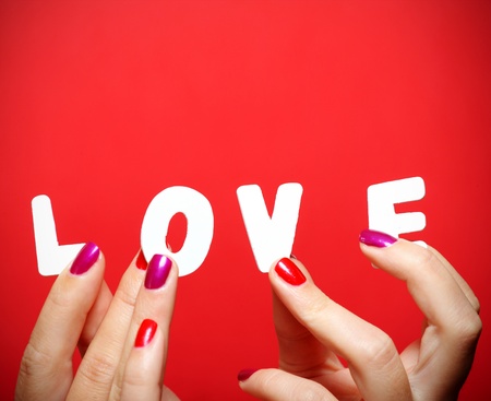 A close up of female hands holding a love inscription over red backgroundの写真素材