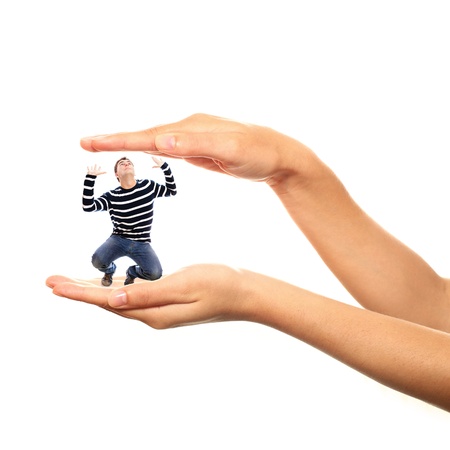 A picture of a young stressed man trapped in big hands over white backgroundの写真素材