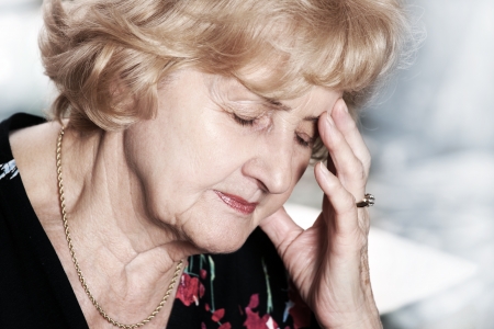 A portrait of a senior lady having headache over dark backgroundの写真素材