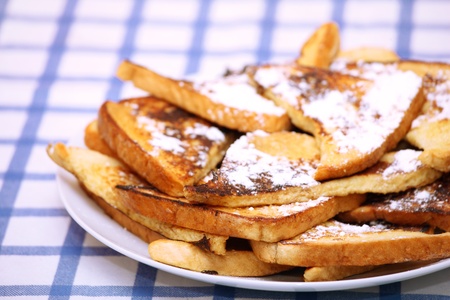 A close-up of a pile of french toast on a white plate