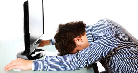 A portrait of a tired businessman resting his head on the keyboard over white backgroundの写真素材