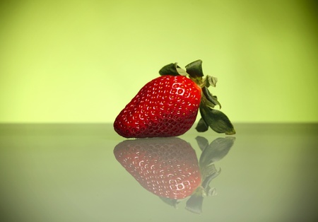 A picture of a fresh strawberry and it's reflection against green backgroundの写真素材