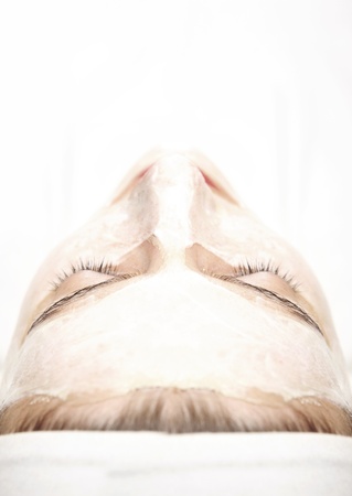 A picture of a young relaxed woman with a facial mask on over white backgroundの写真素材