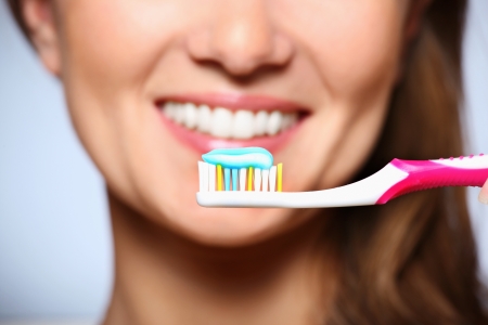 A picture of a toothbrush with toothpaste and a beautiful smile in the backgroundの写真素材
