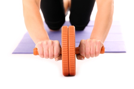 A close-up of a young woman training with AB wheel over white backgrounsの写真素材