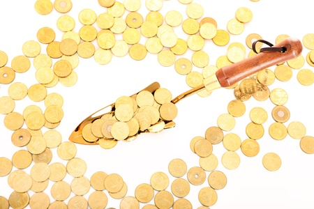 A picture of a small shovel full of golden coins over white backgroundの写真素材