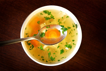 A picture of a bowl of traditional chicken soup served in a bowl over wooden backgroundの写真素材