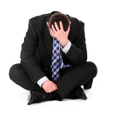 A picture of a disappointed businessman sitting over white backgroundの写真素材