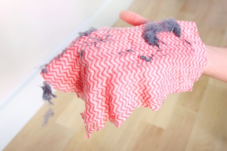 A picture of a hand holding a dirty rag over wooden floorの写真素材