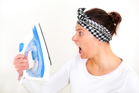 A picture of a tired unhappy housewife shouting at her iron over white backgroundの写真素材
