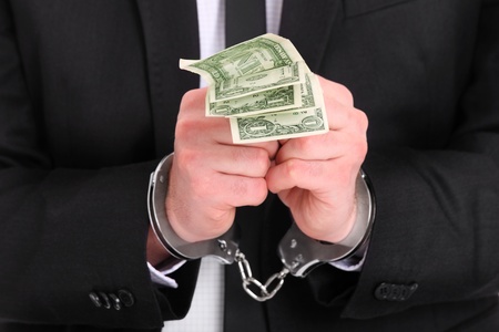 A picture of a businessman in handcuffs holding dollarsの写真素材