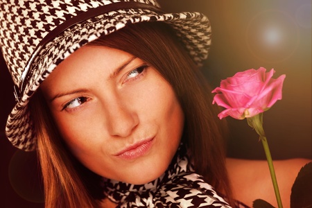 A picture of a beautiful woman looking at a pink rose against dark backgroundの写真素材