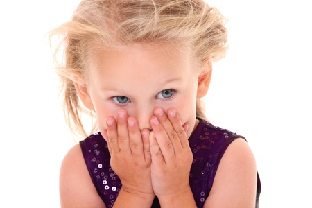 A portrait of a scared little girl hiding her face behind hands over white background
