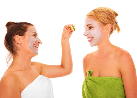 A picture of two girl friends relaxing with facial masks on over white backgroundの写真素材