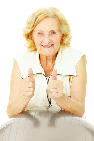 A portrait of a happy senior lady exercising with a ball over white backgroundの写真素材