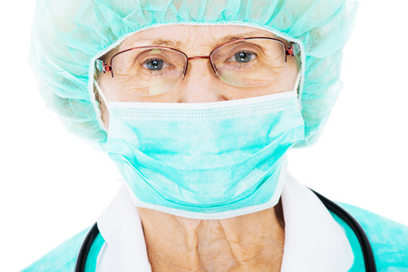 Close-up portrait of senior female surgeon wearing surgical mask and hat isolated over white backgroundの写真素材