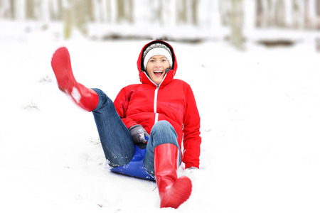 A picture of a pretty woman sliding from the hill in the winter forestの写真素材