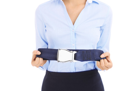 Young stewardess in blue shirt showing belt over whiteの写真素材