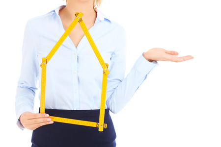 A midsection of a real estate agent showing yellow measure and pointing over white backgroundの写真素材