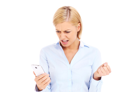 A picture of an angry businesswoman with a cellphone over white backgroundの写真素材