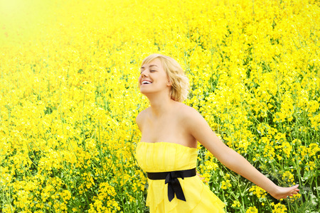 A portrait of a happy woman on a yellow rape fieldの写真素材
