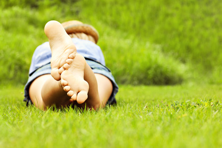 A back picture of a woman lying on green grass with copy space on the rightの写真素材