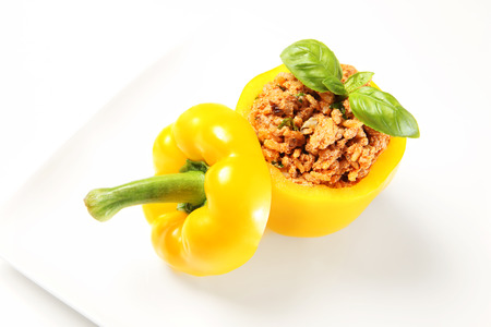 A picture of an unbaked yellow stuffed pepper served on a white plateの写真素材