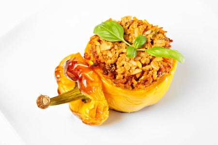 A picture of a yellow stuffed pepper baked and served on a white plateの写真素材