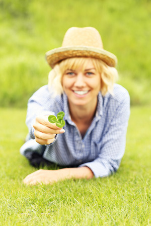 A picture of a woman lying on grass and showing cloverの写真素材