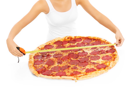 A picture of a woman measuring a huge pizza over white backgroundの写真素材