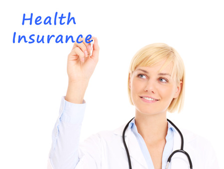 A picture of a young doctor writing "health insurance" on board over white backgroundの写真素材