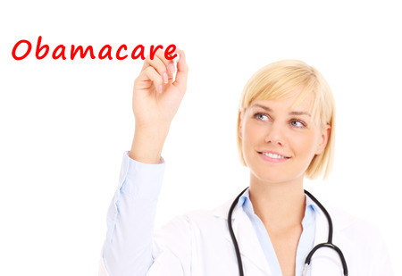 A picture of a young doctor writing "obamacare" on board over white backgroundの写真素材